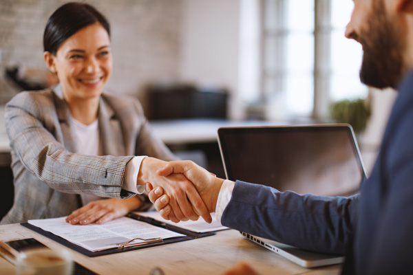 Friendly, smiling business woman shaking hands with client