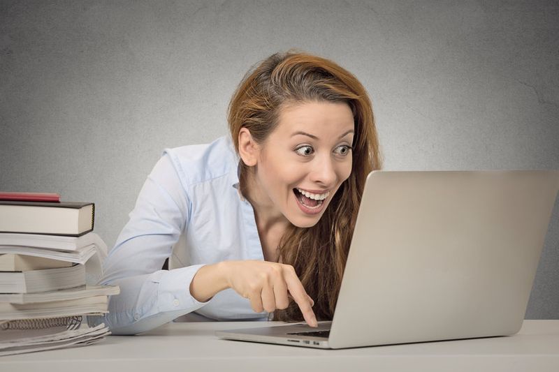 Excited woman exploring dating site on laptop