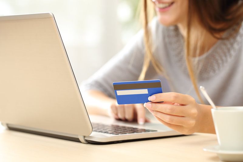 Smiling woman searching for cam sites while holding credit card