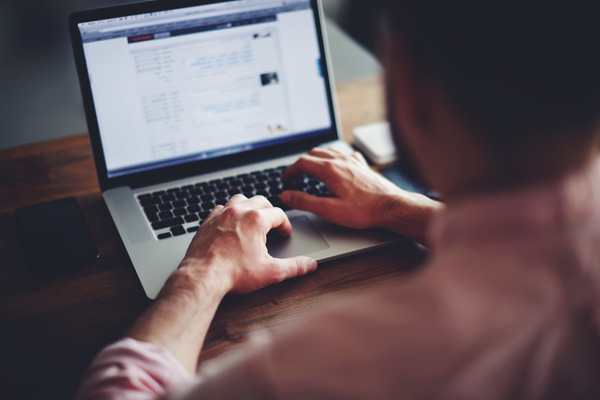 Man scrolling through paysite listings on laptop