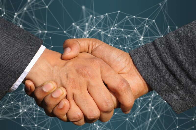 Two men shaking hands with a digital background