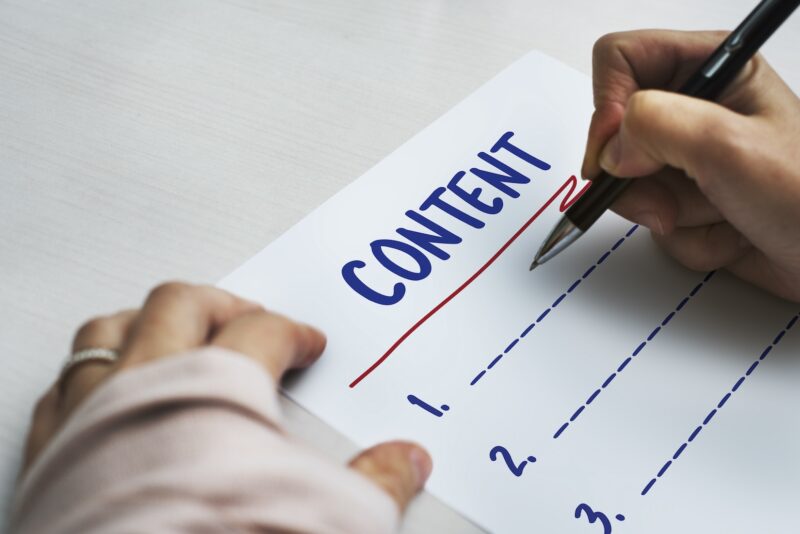 The word content on a piece of paper with a person writing.